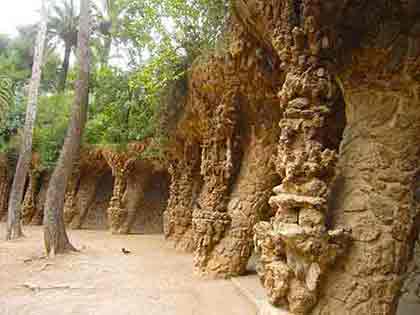 Gaudi's Park Guell in Barcelona, displaying intricate walls amidst lush greenery.
